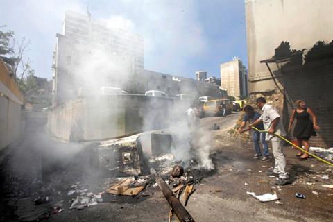File - Civilians douse two garbage containers with water after part-time Electricite Du Liban workers had set them on fire near EDL’s Beirut headquarters, Monday, July 1, 2013. (The Daily Star/Mahmoud Kheir)