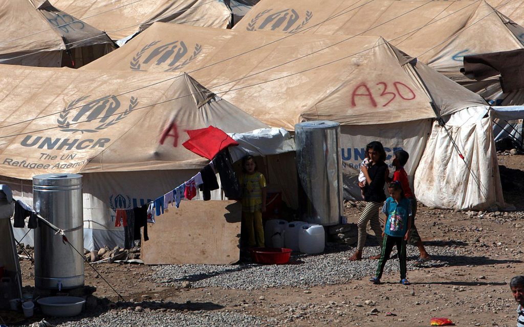 Syrian refugees, who fled the violence in Syria, walk at a new refugee camp in Arbil in Iraq's Kurdistan region