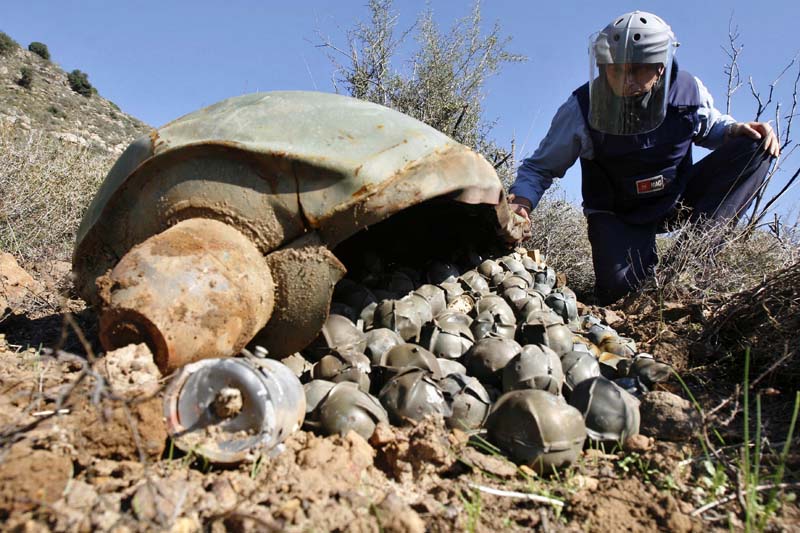 Mines Advisory Group (MAG) Technical Field Manager Nick Guest inspecting a Cluster Bomb Unit in the southern village of Ouazaiyeh, Lebanon, in 2006. (AP Photo/Mohammed Zaatari, File)